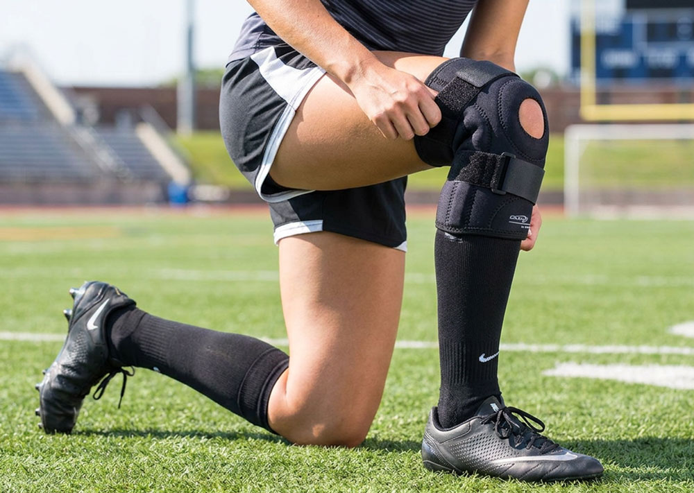 Athlete applying the DonJoy Performer Hinged Patella Knee Brace