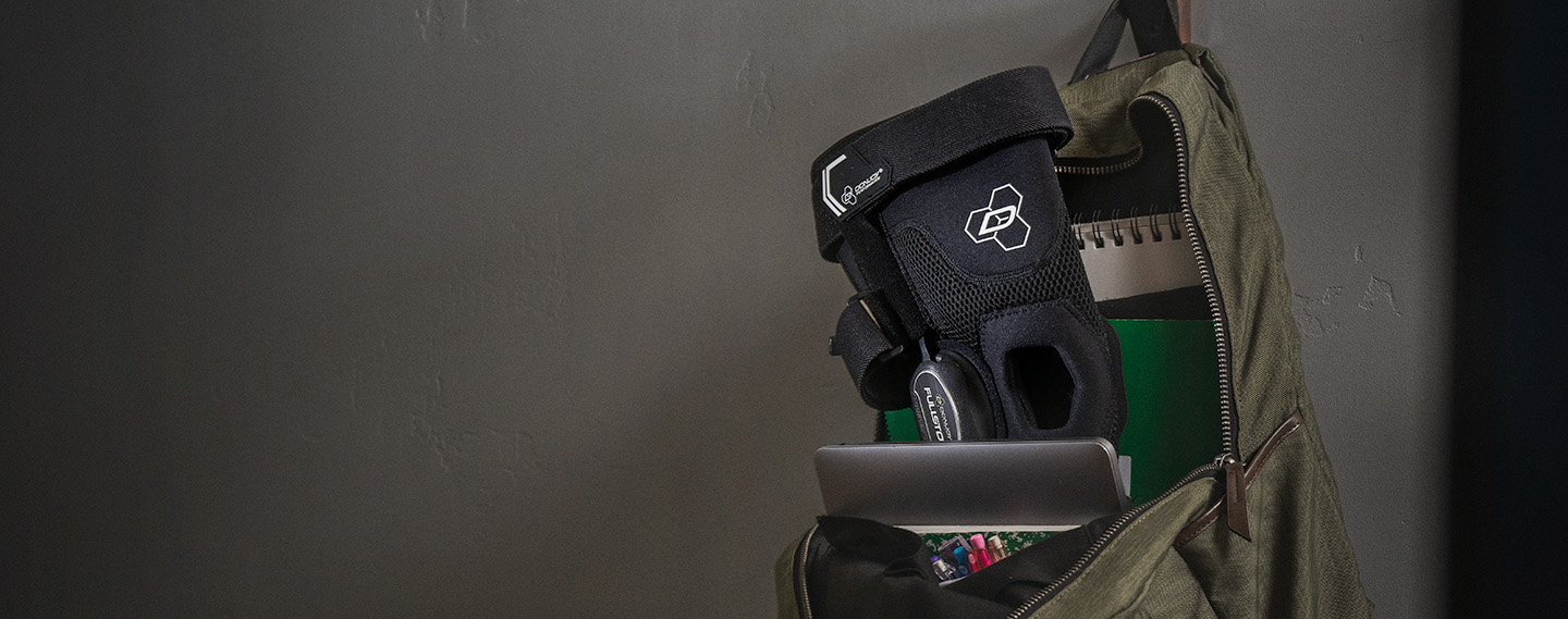 DonJoy Performance Fullstop knee brace sitting inside of a school backpack hanging on the wall