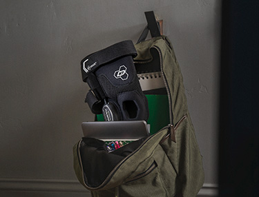 DonJoy Performance Fullstop knee brace sitting inside of a school backpack hanging on the wall