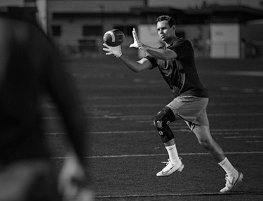 Athlete wearing FullStop Knee Brace catching a football