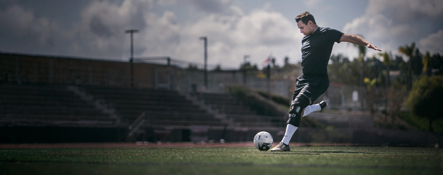 Athlete wearing the DonJoy Performance Bionic™ FullStop Knee Brace kicking a soccer ball