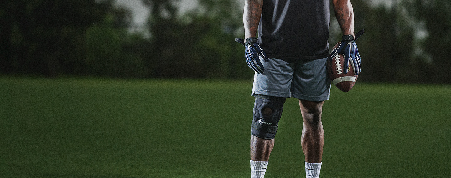 Athlete wearing the DonJoy Performance Bionic™ Knee Brace holding a football