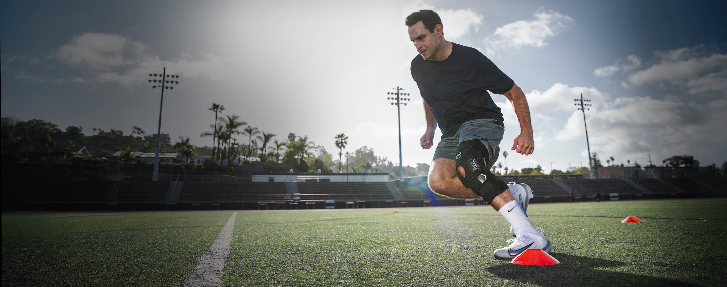 Athlete wearing knee brace running football drills