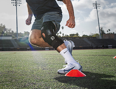 Athlete wearing knee brace running football drills