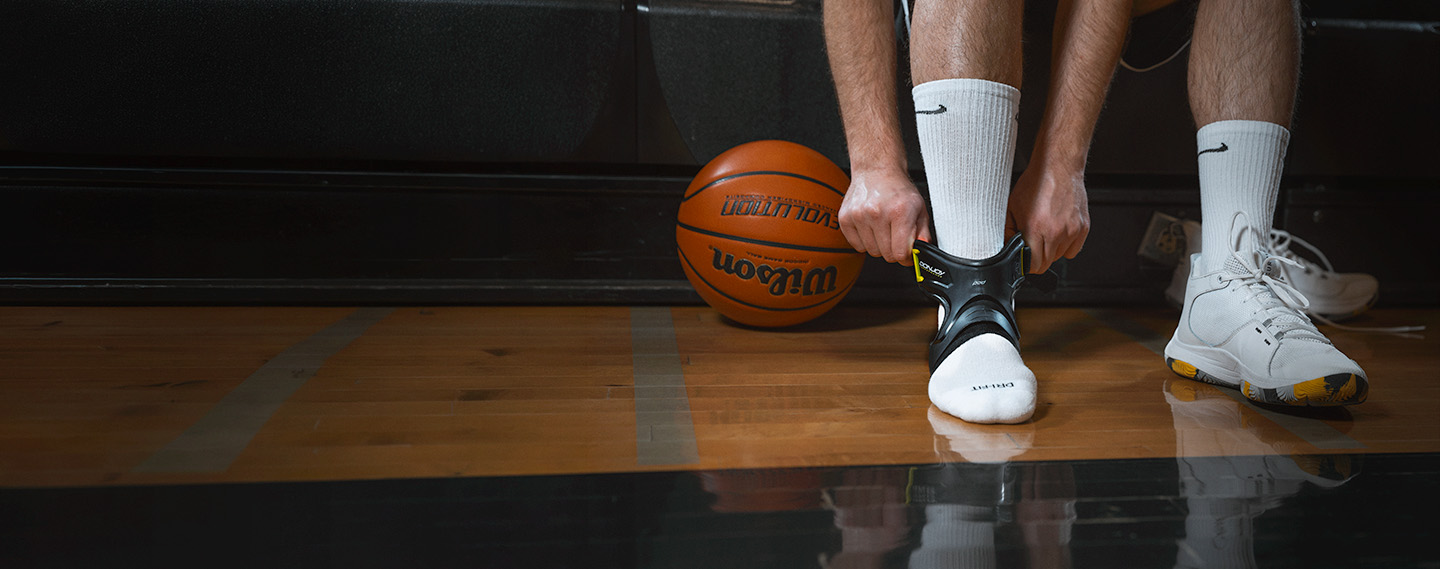 Athlete wearing the POD ankle brace sitting in the bleachers