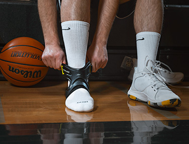 Athlete wearing the POD ankle brace sitting in the bleachers