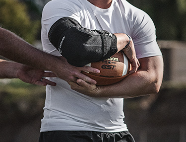 Athlete wearing a DonJoy Performance Bionic Elbow Brace playing football