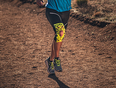 Athlete wearing webtech knee brace trail running