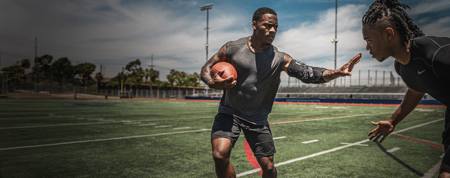 Athlete wearing elbow brace running with the football
